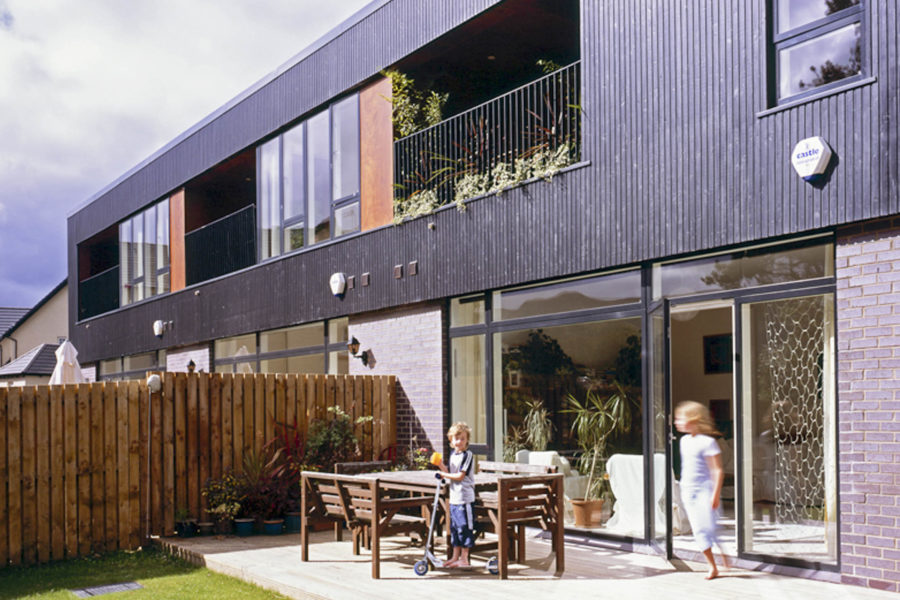 Princess Gate housing, Edinburgh. Exterior view of rear with garden. Brick and black timber cladding. Malcolm Fraser Architects