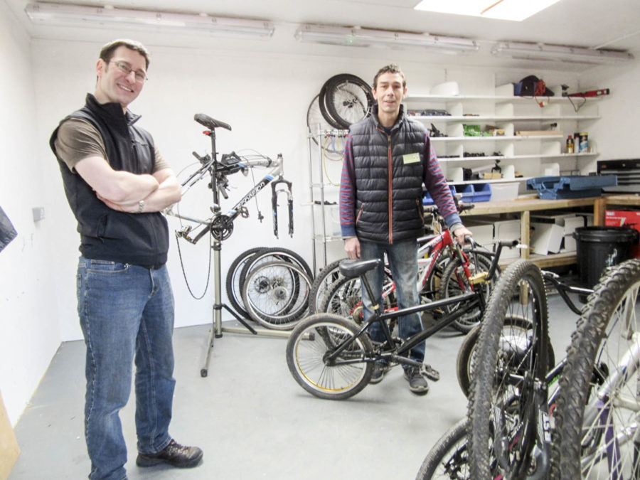 In the bike workshop at Bridgend Farmhouse. Two staff work with bikes