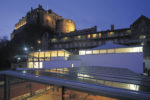 Dance Base, Edinburgh. View over roof of studios to Edinburgh Castle. Shown at night. Malcolm Fraser Architects