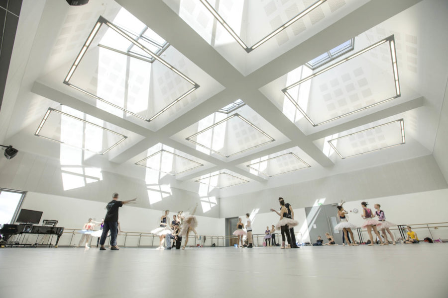 Dance studio with piano, dancers, intstructor. Looking up to the roof